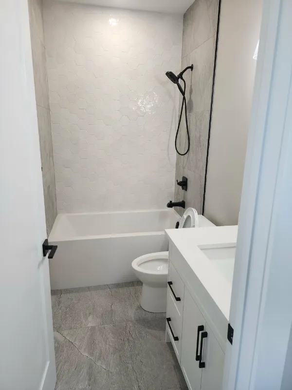 Bathroom with soaker tub, grey tile surround and white vanity