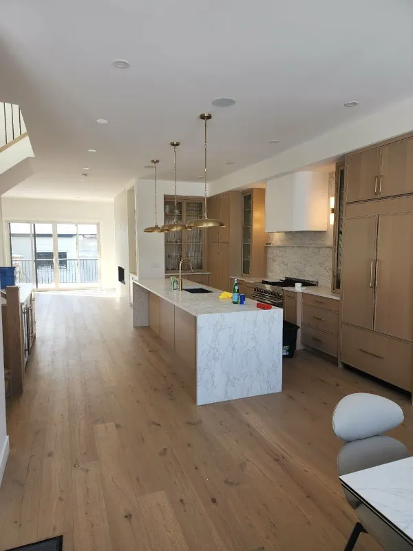 Open-concept kitchen renovation with marble waterfall island and pendant lights