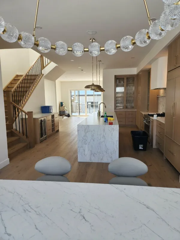 Marble waterfall island with open staircase and crystal chandelier