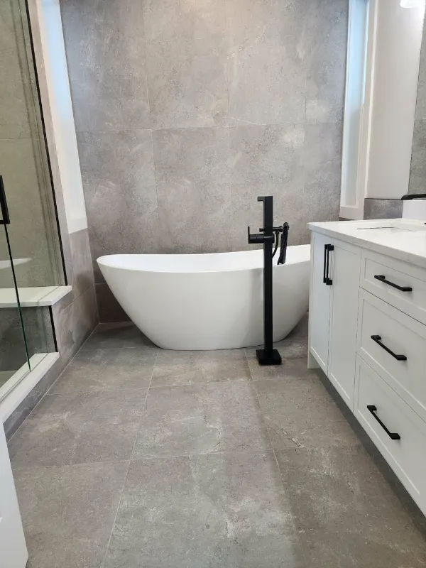 Freestanding tub with black floor-mounted faucet and large-format tile