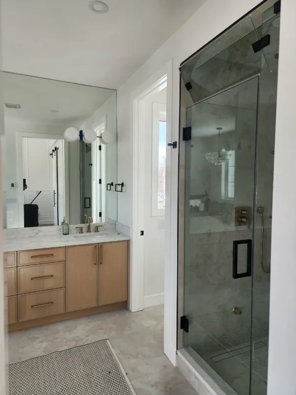Master ensuite with wood vanity and frameless glass shower